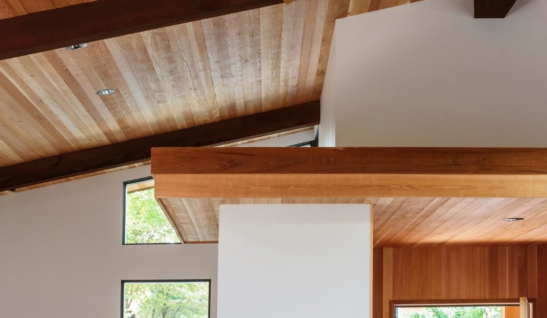 A modern and minimalistic residential home interior featuring elevated faux wood beams running along the sloped ceiling.