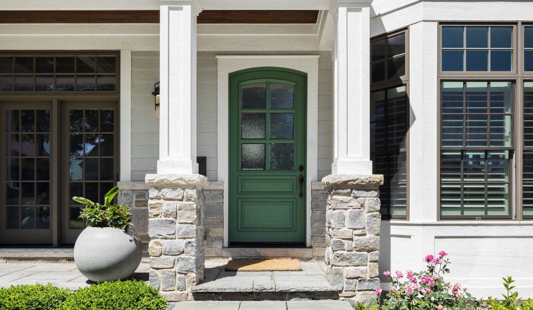 The front door entrance of a newly renovated home. The porch features columns with aluminum wraps and stone bases.