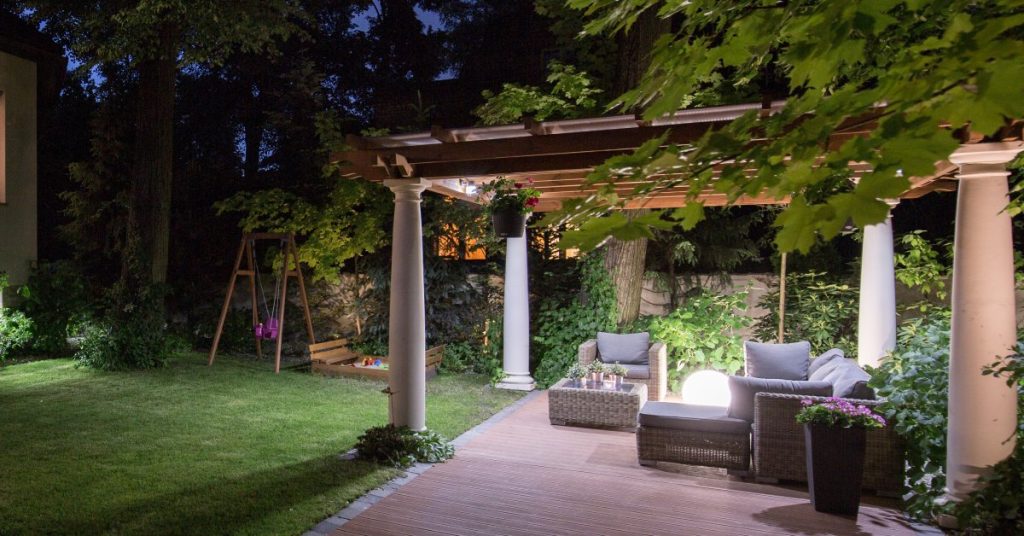 A luxurious villa backyard oasis, complete with fine landscaping and a pergola supported by aluminum-wrapped columns.